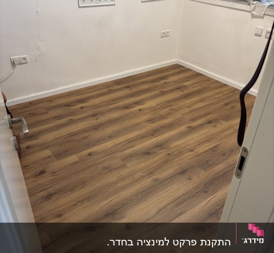 רצפת פרקט בחדר עם פוסטרים על הקיר